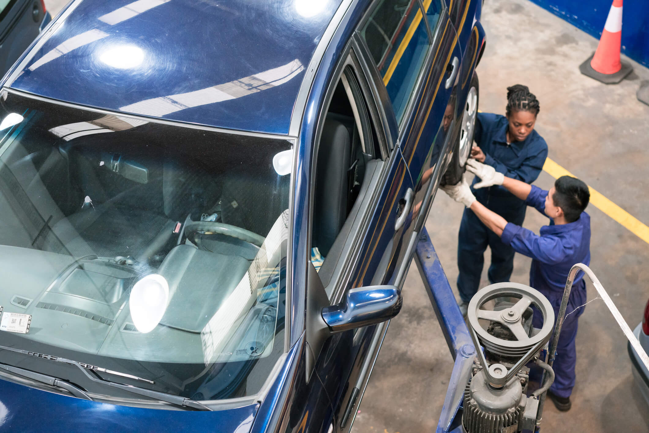 Car mechanics working on vehicle lift